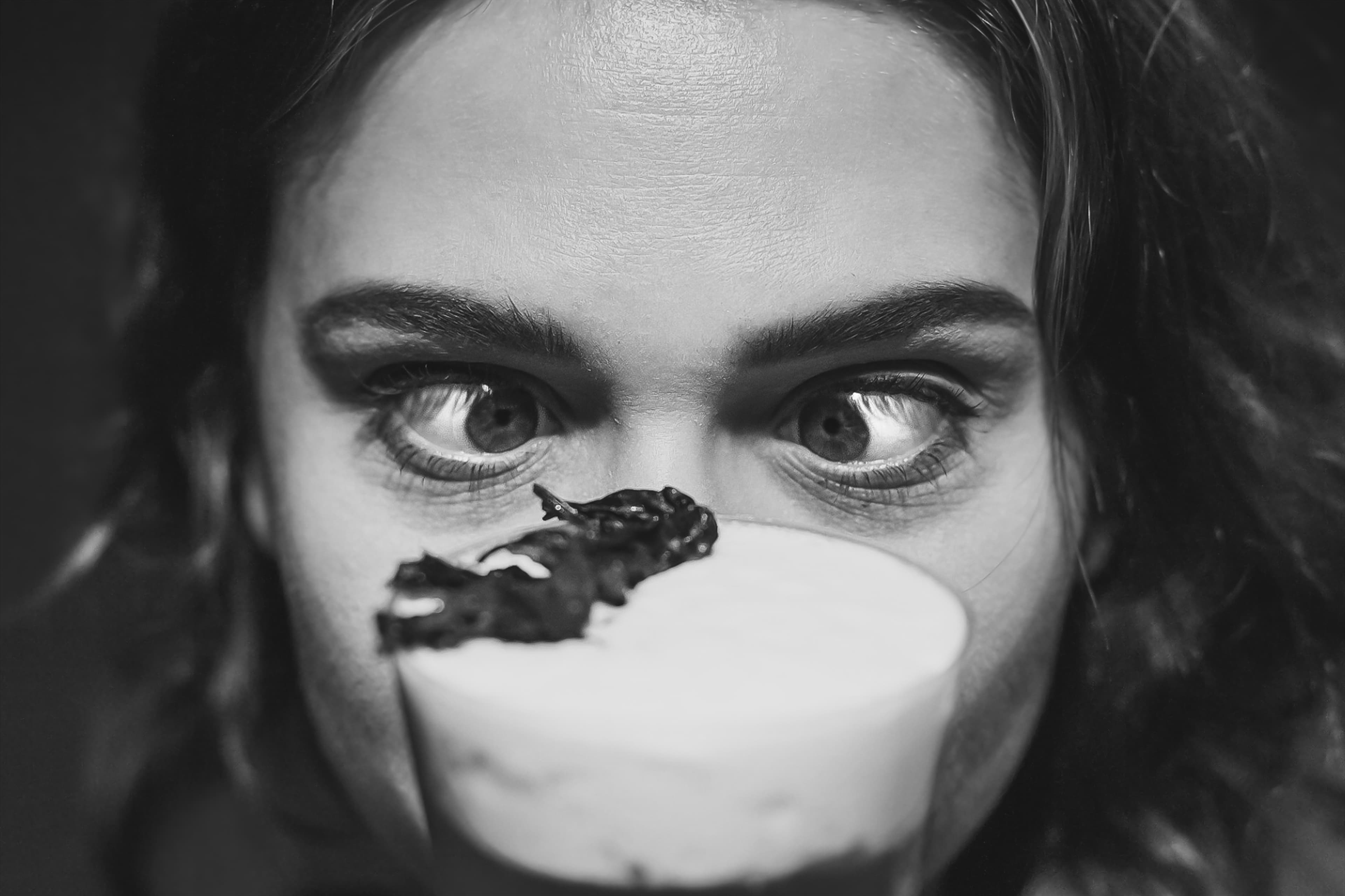 Black and white close portrait behind a cup